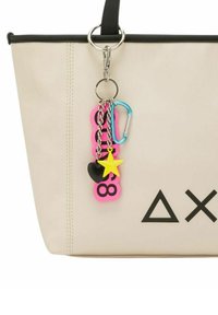 Borsa tote beige con bordi neri, dotata di un anello d'argento e colorati ciondoli a forma di chiave, tra cui un design rosa, nero e giallo.