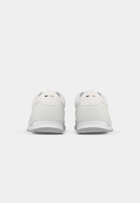 Pantofi sport albi, cu un superior din piele netedă și suede, design rotund și talpă din cauciuc texturat. Branding minimal și profil elegant.