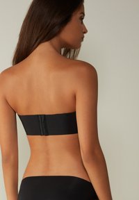 Zwarte strapless bandeau top van gladde stof, met een haaksluiting op de rug en zonder zichtbare versieringen.