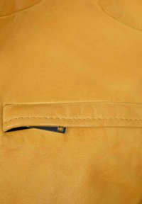 Gelbes Lederetui mit einer glatten Textur. Verfügt über eine gesäumte Öffnung und ein metallisches rechteckiges Akzent auf der Vorderseite.