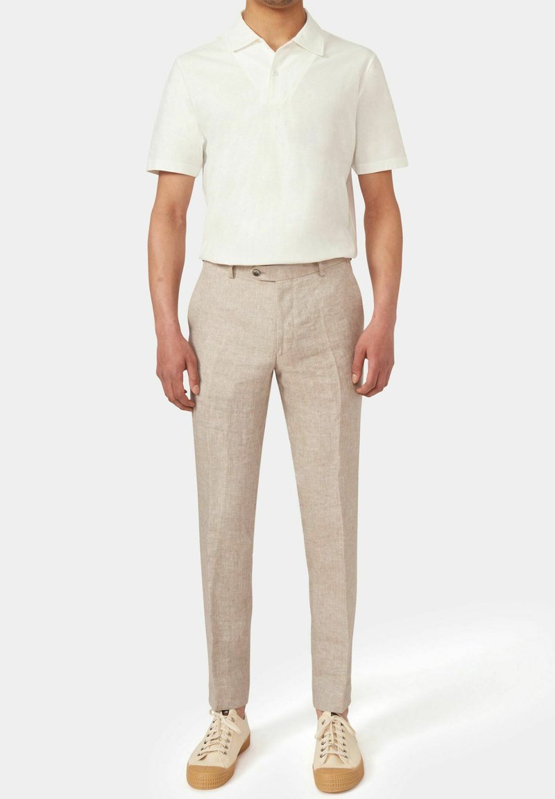 Outfit da uomo composto da una polo di lino beige chiaro, pantaloni beige chiaro su misura e sneakers crema con suole texturate.