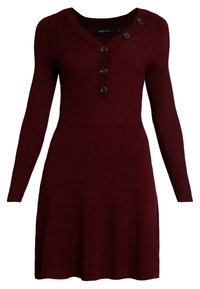 Abito a coste color marsala con maniche lunghe, caratterizzato da un collo a V e quattro bottoni decorativi sul davanti. Design della gonna svasata.