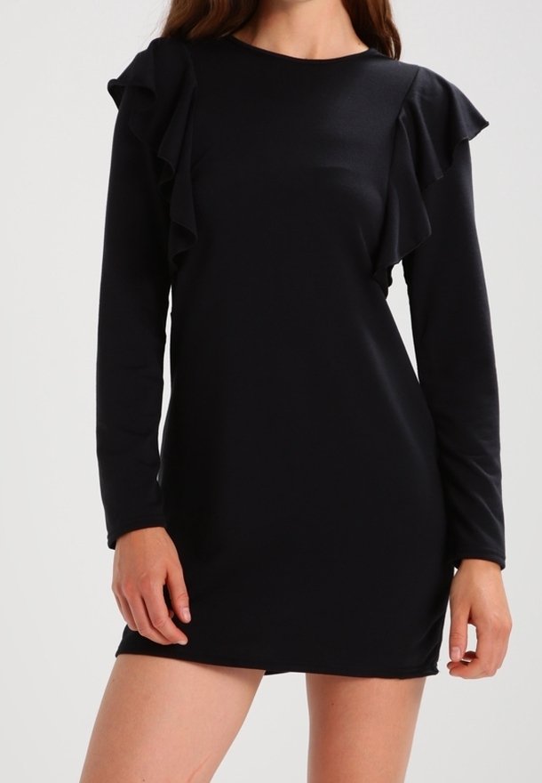 Vestido negro de manga larga con acentos de volantes en los hombros, silueta ajustada y textura suave. Largo hasta la rodilla, con un sencillo escote redondo.