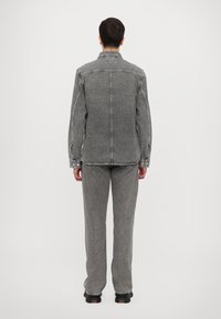 Gray denim shirt and matching pants, featuring shoulder seams, button closures, and a straight-leg fit. The texture appears slightly coarse.