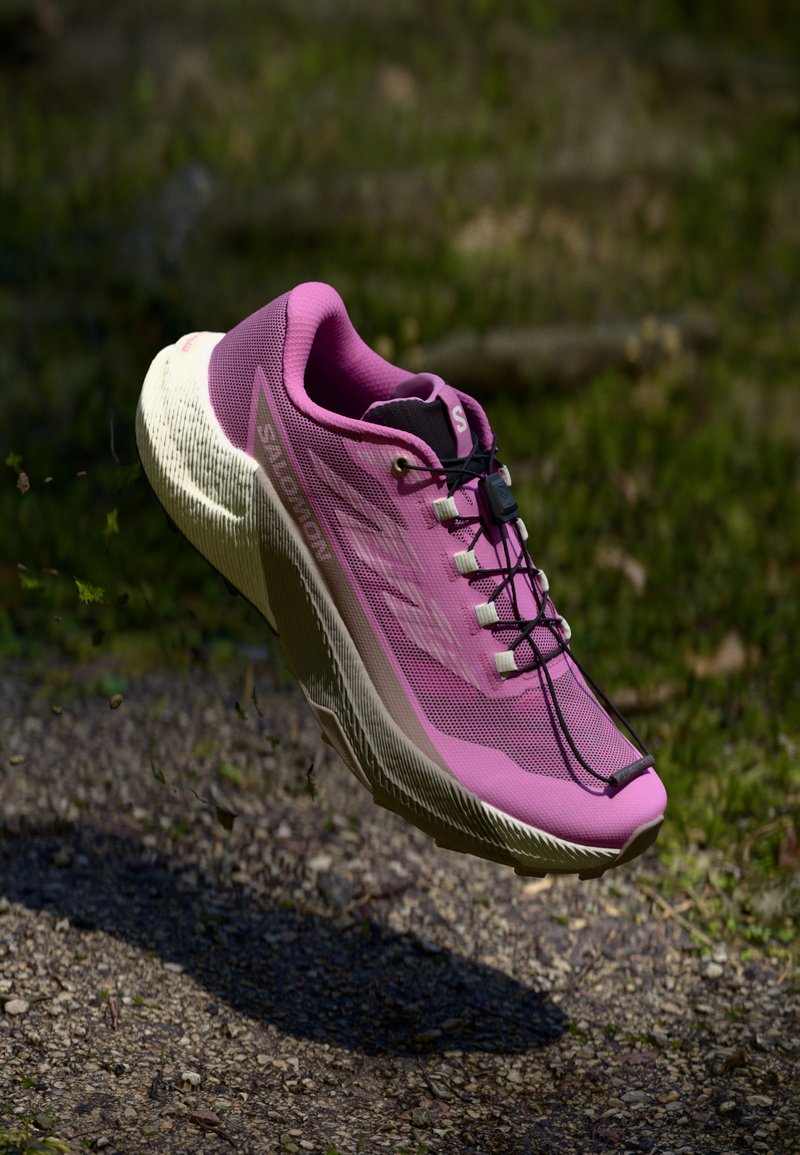 Bottines de course légères de couleur rose avec une tige en maille respirante, une semelle texturée blanche et des lacets noirs. Présente un design épuré pour la performance.