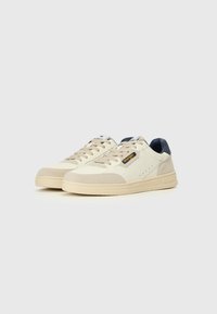 Baskets en cuir et daim beige avec une semelle blanche, bout rond et accents bleus. Comprend le logo de la marque et des détails perforés.