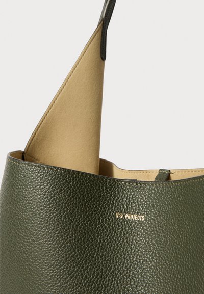 Sac à main en cuir vert olive avec un extérieur texturé et un intérieur beige. Doté d'un logo doré et d'un design minimaliste.