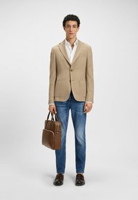Beige checkered blazer, white shirt, blue jeans; brown leather bag with silver accents; brown shoes. Simple, modern design.
