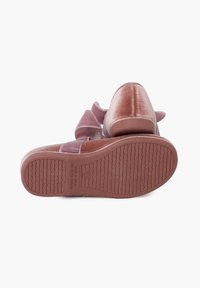 Zapato de terciopelo rosa con suela de goma texturizada. Presenta una correa ancha con un acento de lazo y una punta redonda suave. Construcción robusta.