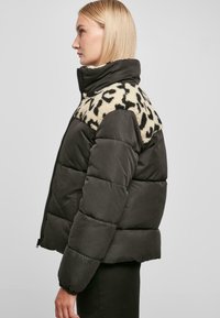 Donkergroene pufferjack met een gestructureerde kraag in beige en zwarte luipaardprint. Voorzien van een ritssluiting aan de voorkant en elastische manchetten voor extra warmte.