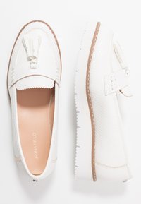Hvite loafers laget av teksturert syntetisk materiale, med en dekorativ dusk og en kontrastfarget beige såle med teksturert grep.