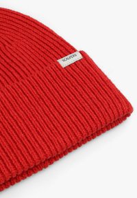 Gorro rojo de punto con textura acanalada, con una pequeña etiqueta que lleva la inscripción "SCALPERS" en el lateral. Material suave y cálido para el frío.