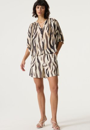 Korte mouwen, knoopsluitingsshirt en bijpassende korte broek in beige stof met een zwart-bruine zebrastripleer. Lichtgewicht en gestructureerd materiaal.