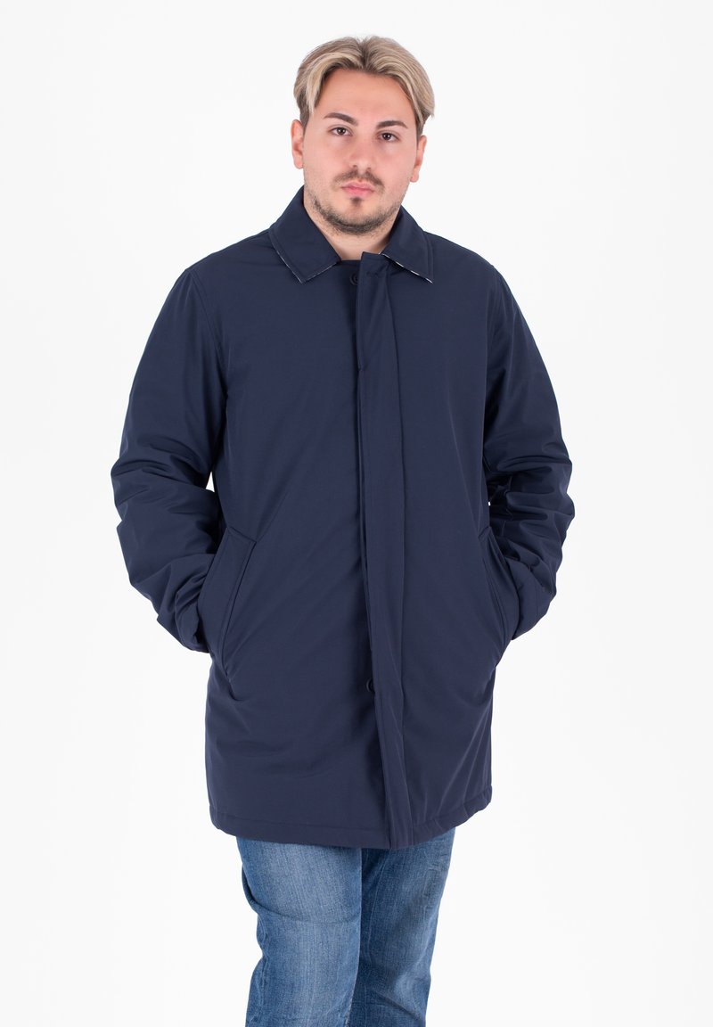 Cappotto isolato blu navy con colletto e chiusura a bottoni, dotato di due tasche laterali e una trama liscia. Adatto per il clima fresco.