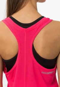 Růžový atletický top s designem racerback, s horizontální žebrovanou strukturou a černou spodní vrstvou. Obsahuje detail loga.