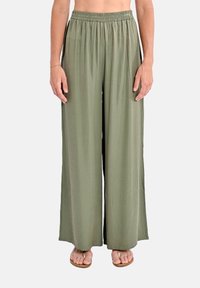 Pantaloni larghi in tessuto verde oliva, con una cintura elastica. Texture morbida con una caduta fluida. Abbinati a sandali piatti.