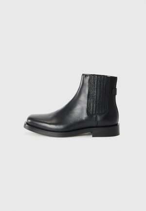 Black leather ankle boots featuring elastic side panels, a smooth finish, rounded toe, and a low stacked heel.