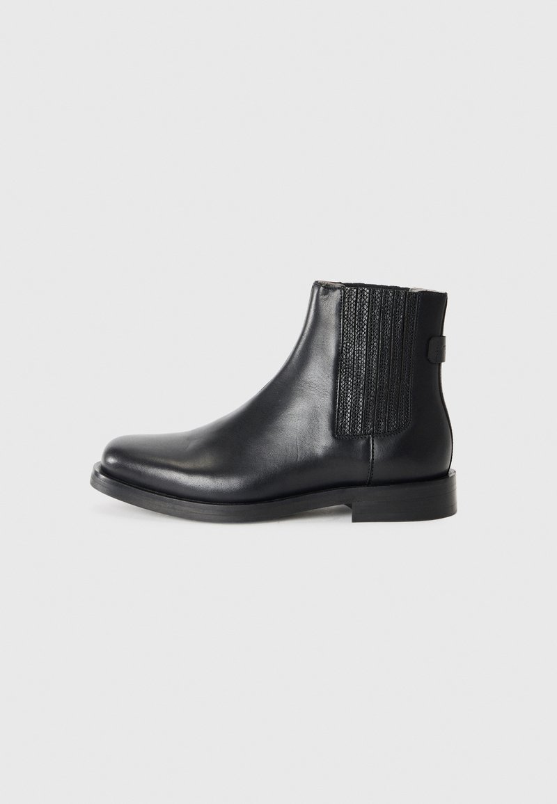 Bottines en cuir noir avec des panneaux latéraux élastiques, une finition lisse, un bout arrondi et un petit talon empilé.