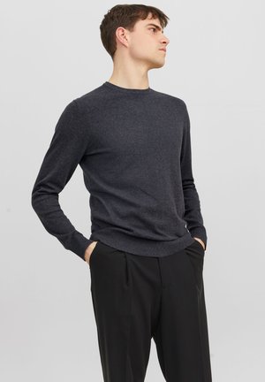 Maglione a maglia grigio scuro con scollatura rotonda, maniche lunghe e orlo a coste, abbinato a pantaloni neri su misura. Tessuto morbido.