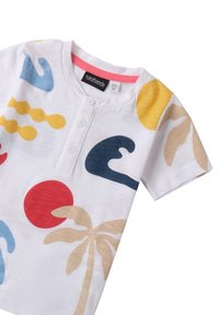 Camiseta blanca de manga corta con patrones abstractos coloridos, que incluyen olas azules, círculos rojos, formas amarillas y estampados de palmeras marrones.
