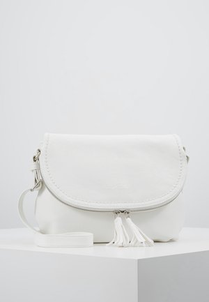 Sac bandoulière en cuir blanc avec rabat arrondi, fermeture éclair argentée et deux pompons, posé sur une surface blanche sur un fond clair.