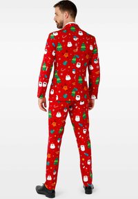 Costume de Noël rouge avec des motifs festifs d'arbres, de visages de Santa et de rennes. Fabriqué en tissu texturé, design ajusté et coupe slim.