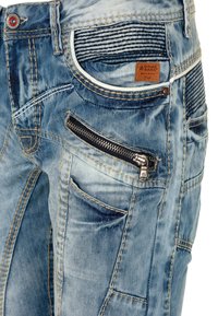Blaue Denim-Jeans mit einem verwaschenen Finish, mehreren Taschen, einer Reißverschlusstasche und kontrastierenden Nähten. Markenlabel an der Taille sichtbar.