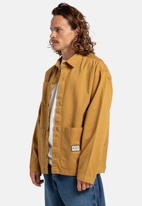 Mosterdgele button-up shirt van katoen, met twee voorzakken en een label aan de rechteronderkant, met een relaxed fit en lange mouwen.