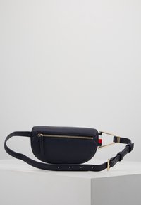 Borsa a tracolla in pelle blu navy con una cerniera dorata, forma piatta, tracolla regolabile e accento a strisce vicino all'hardware. Texture morbida con una grana sottile.