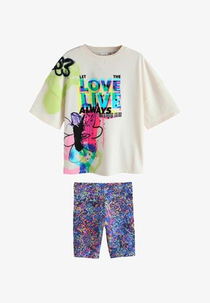 Cremefarbenes Oversize-T-Shirt mit buntem Text und abstraktem Blumendesign, kombiniert mit Shorts mit mehrfarbigem Spritzmuster.