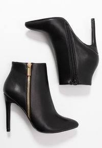 Stivali neri in pelle fino alla caviglia con punta appuntita e tacco a stiletto. Presentano una cerniera dorata di lato. Texture liscia, design elegante.