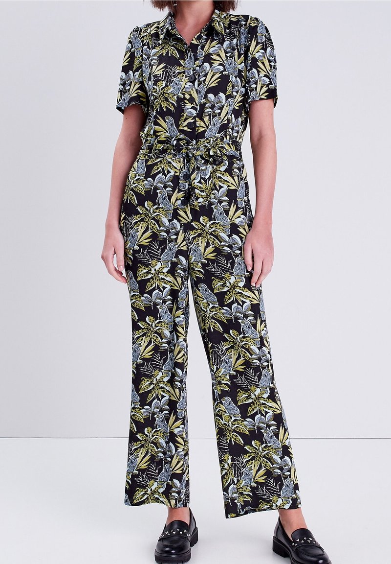 Combinaison noire à manches courtes, ornée d'un motif floral vibrant en vert et bleu. Comprend un cordon de serrage à la taille et un pantalon à jambes larges.