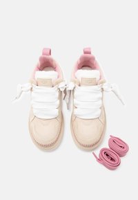 Ανοιχτό μπεζ αθλητικά παπούτσια με λευκά κορδόνια, απαλό ροζ εσωτερικό και λεπτές ραφές. Περιλαμβάνονται δύο επιπλέον ροζ κορδόνια.