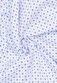 Tessuto di cotone con uno sfondo azzurro chiaro, caratterizzato da un motivo ripetuto di cerchi e quadrati blu scuro. Texture liscia.