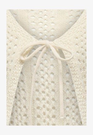 Lehký krémový pletený cardigan s otevřeným vzorem, uvázaný na krk páskem ze stejného materiálu. Ozdobený jemnými vzory.