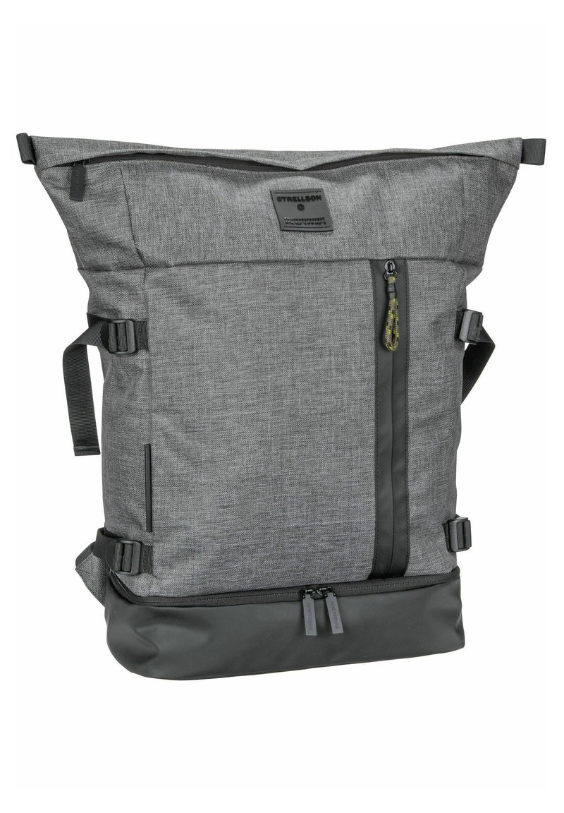 Grauer Stoff-Rucksack mit Roll-Top-Design, schwarzem Boden, äußerer Reißverschlusstasche, verstellbaren Tragen und Markendetails.