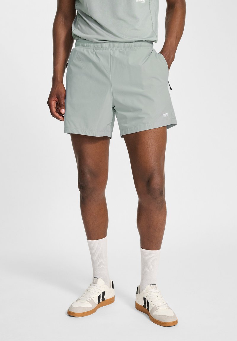Ljusgröna, lätta shorts med elastisk midja, sidofickor och en liten logotyp. Bärs med vita sneakers och strumpor.