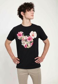 Černé bavlněné tričko s krátkým rukávem a kulatým výstřihem, které má květinový siluetu Mickey Mouse v růžové a bílé barvě s zelenými akcenty.