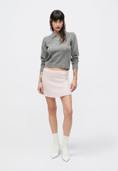 Sivý pletený sveter s golierom a vzorom diamantov, v kombinácii s ružovou mini sukňou. Dokončené bielymi ponožkami a špicatou obuvou.