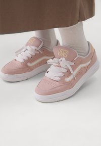 Helle rosa Vans-Sneaker mit weißen Schnürsenkeln, aus Wildleder und mit einer glatten Gummisohle. Verfügt über einen charakteristischen Seitenstreifen in einer helleren Nuance.