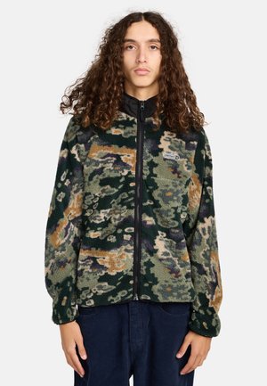 Fleecejakke i grøn camouflage mønster med nuancer af brun og lilla, med en sort lynlås fortil og en brystlomme. Løs pasform.