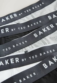 Pile de boxers pour hommes avec ceintures élastiques noires portant l'inscription "BAKER by TED BAKER" en texte blanc, en noir, gris et blanc.