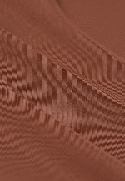 Terakota audums ar smalku, paralēlu ribu tekstūru un maigu apdari, izceļoties ar bagātu, siltu krāsu, salocīts, lai piešķirtu dimensiju.