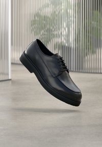 Chaussure habill ée en cuir noir à texture lisse, bout arrondi et design à lacets. Dotée d'une semelle rembourrée et d'une silhouette élégante.