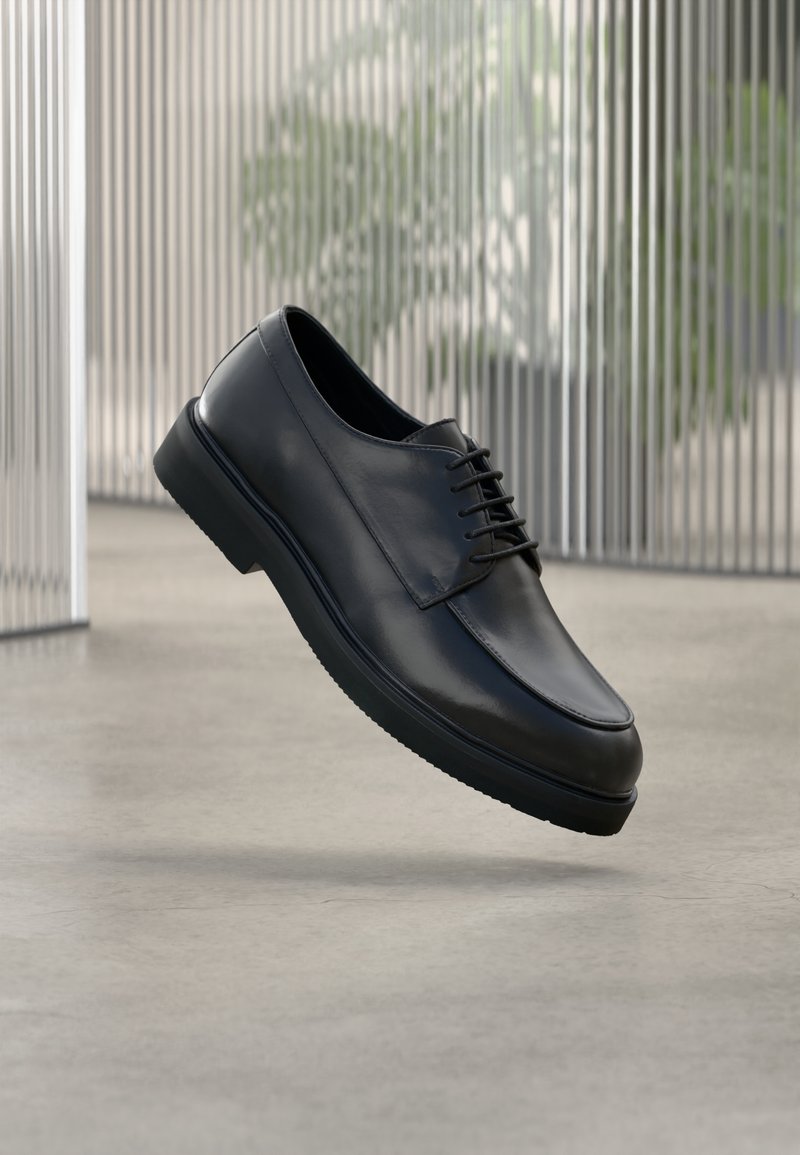 Chaussure habillée en cuir noir à texture lisse, bout arrondi et design à lacets. Dotée d'une semelle rembourrée et d'une silhouette élégante.