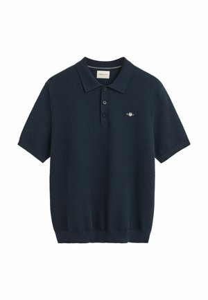 Navyblaues Poloshirt mit kurzen Ärmeln, das aus einem strukturierten Stoff gefertigt ist, über eine Knopfleiste mit drei Knöpfen verfügt und ein kleines gesticktes Logo auf der Brust hat.