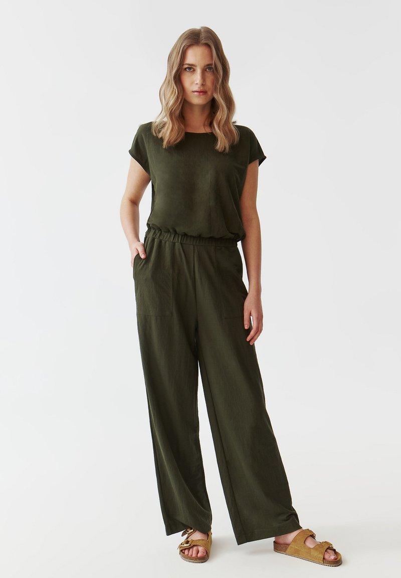 Top verde olive cu mâneci scurte și croială lejeră, asortat cu pantaloni largi verde olive, dotati cu un brâu elastic și buzunare laterale.