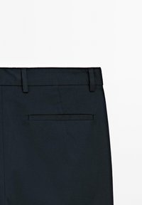 Pantalons noirs à devant plat, avec une poche au centre à l'arrière, texture lisse et passants de ceinture à la taille.
