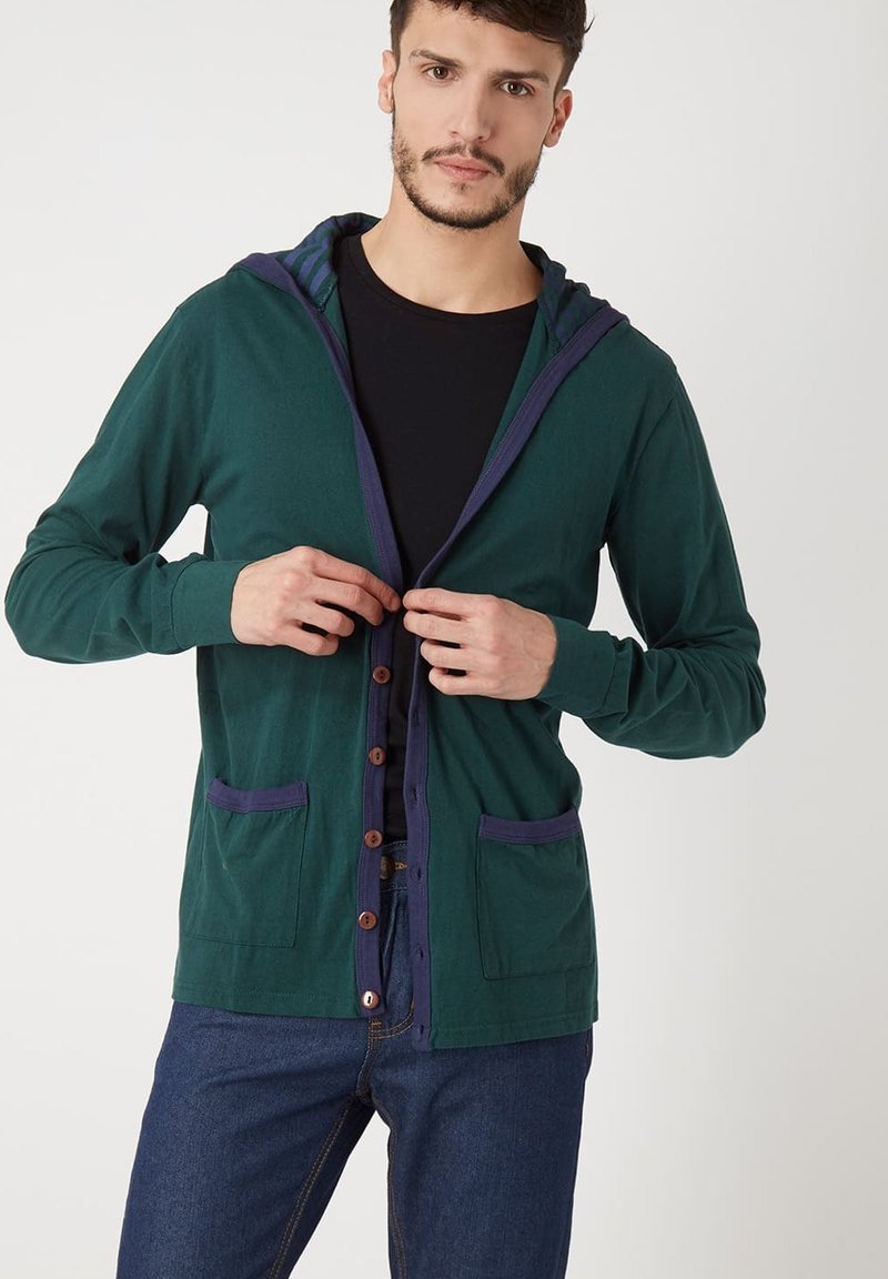 Cárdigan verde oscuro con capucha, acentos azules contrastantes, botones en el frente y bolsillos laterales, hecho de una tela suave. Diseño simple.