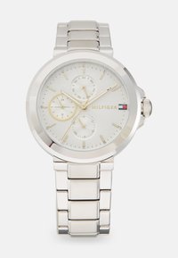 Montre en acier inoxydable argenté avec un cadran rond, un cadran gris clair, trois sous-cadrans, des index en cristal et un bracelet poli.